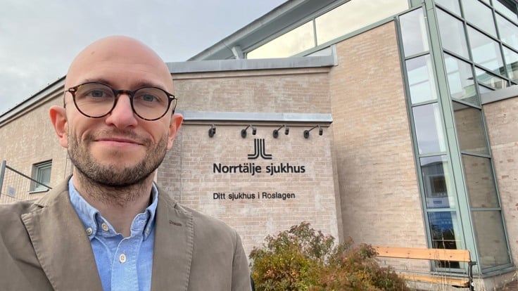 Man utanför byggnad med texten Norrtälje sjukhus.