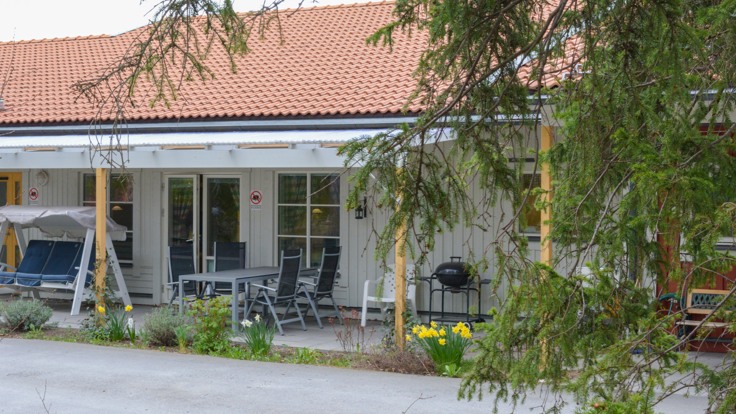 Altan med utemöbler framför vitt hus