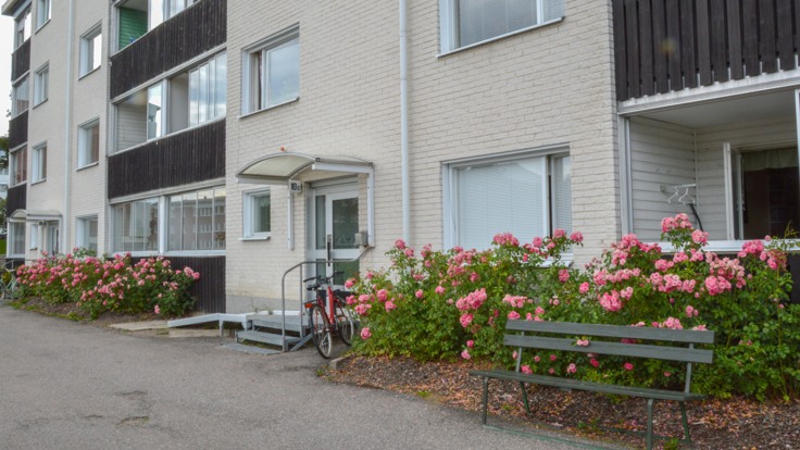 Vitt hus med balkonger, blommande buskar framför