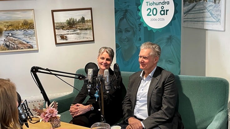 Två personer sitter i en soffa bakom två mickar