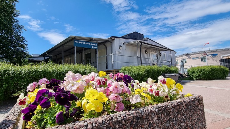 Exteriör av Norrtälje södra vårdcentral med blommande penséer