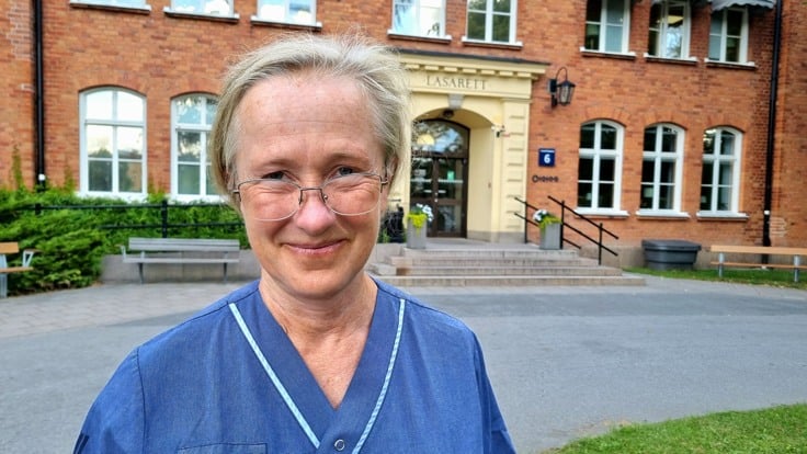 Kvinna står framför tegelbyggnad.