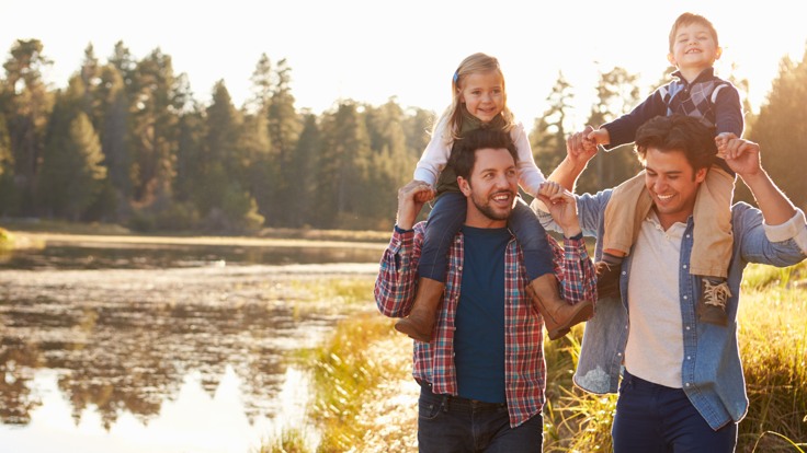 Familj med två män och två barn går promenad i skogen