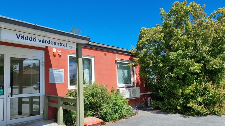 Exteriör från Väddö vårdcentral, entrén och grönskande träd.
