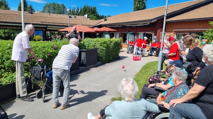 Äldre spelar bowling utomhus på ett äldreboende.