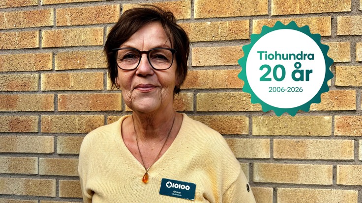 Person i gul tröja och namnskylt står mot tegelvägg.