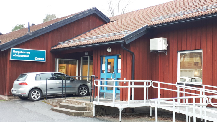 Fasad på rött hus med bil framför. Skylt där det står Bergshamra vårdcentral.