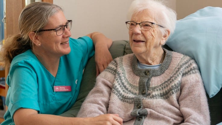 En kvinna pratar med en kvinna i turkos skjorta.