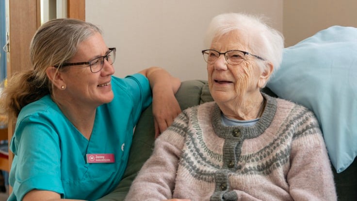 En kvinna pratar med en kvinna i turkos skjorta.