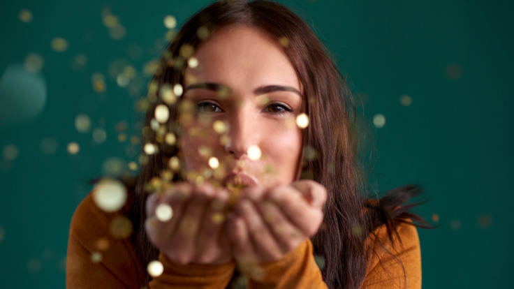 Kvinna blåser glitter från händerna.