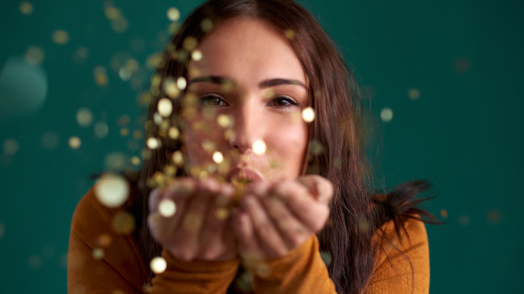 Kvinna blåser glitter från händerna.