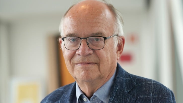 En man i kostym står i en korridor.