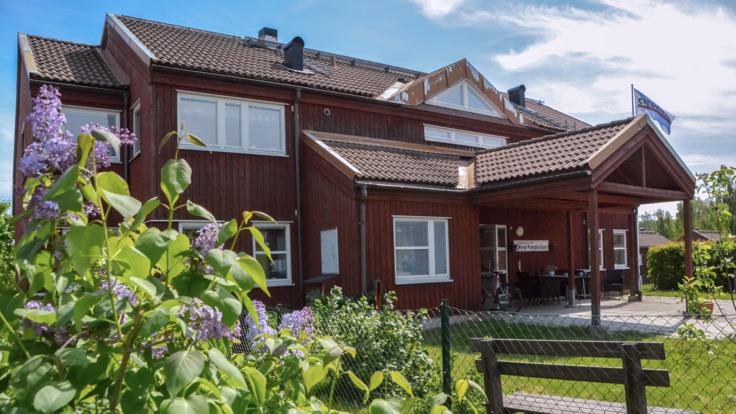 Röd trävilla med lummig trädgård