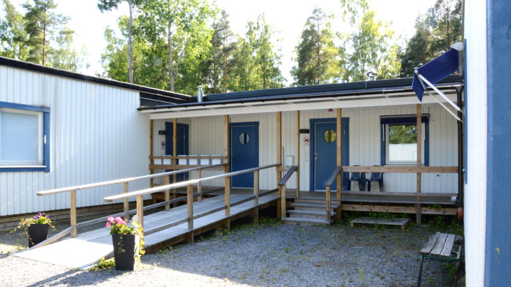 Vitt enplanshus, gård med grus och blommor