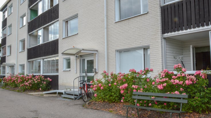 Vitt hus med balkonger, blommande buskar framför