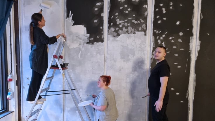 Tre personer målar vägg.