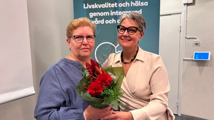 Två kvinnor som står bredvid varandra. En av dem håller en blombukett.