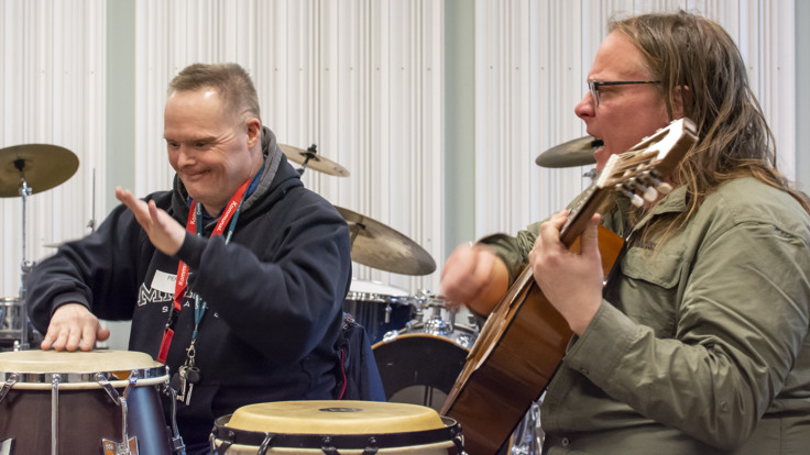 Två män spelar trummor och gitarr med inlevelse.