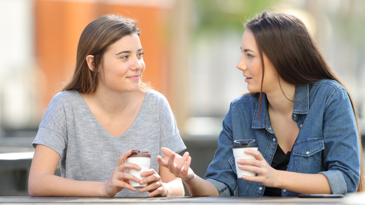 Två kvinnor sitter och dricker kaffe.