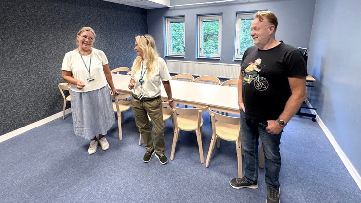 En grupp människor som står utspridda i ett rum.