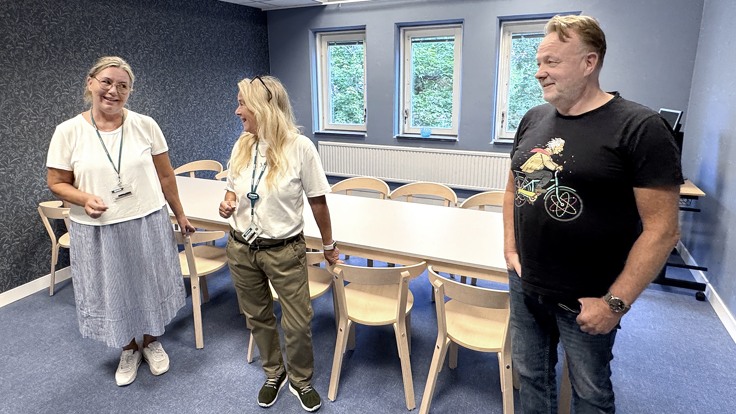 En grupp människor som står utspridda i ett rum.