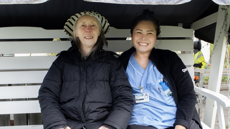 Två kvinnor sitter i en vit hammock.