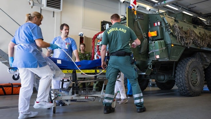 En grupp medicinsk personal vid ett militärfordon.