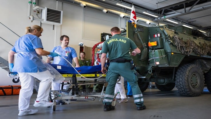 En grupp medicinsk personal vid ett militärfordon.