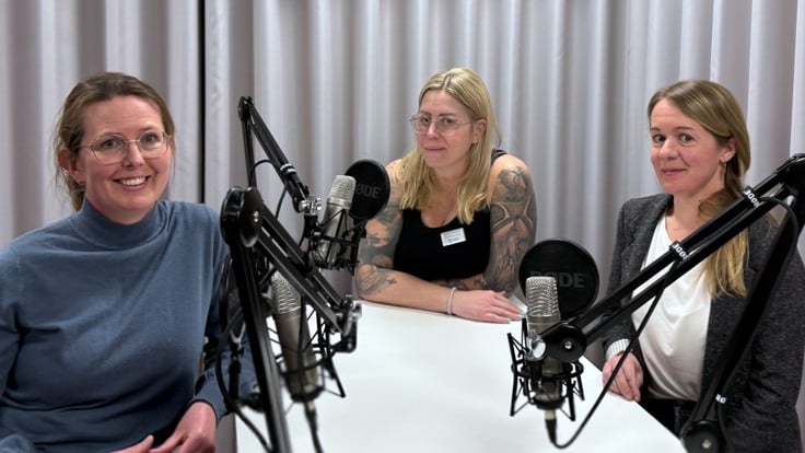 Tre kvinnor sitter vid ett bord framför mikrofoner.