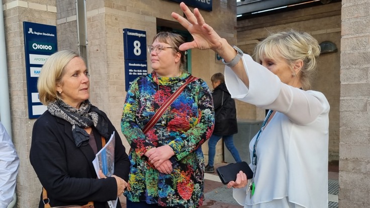 Två kvinnor utanför Norrtälje sjukhus. En tredje kvinna pekar på en del av bygganden.