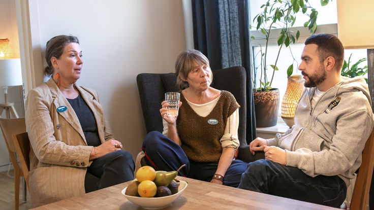 Tre personer sitter i fåtöljer och pratar med varandra