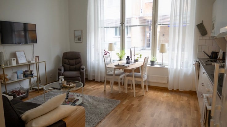 Ett vardagsrum med köksdel och soffmöbler