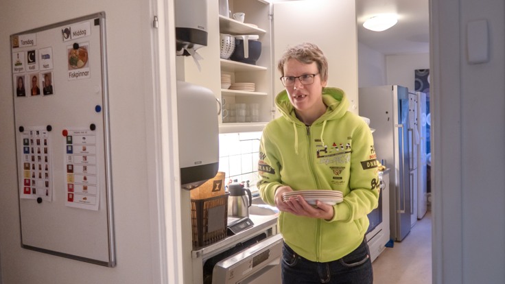 Kvinna med tallrikar i handen, på väg att duka