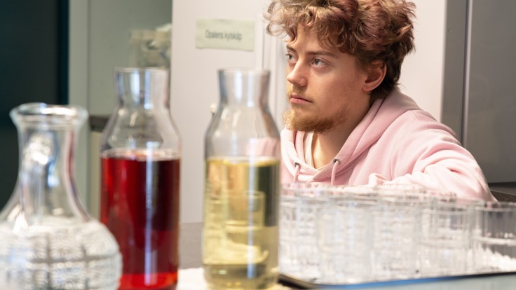 Två flaskor saft. En deltagare sitter bakom i cafékök