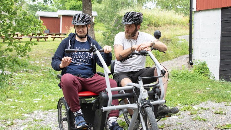 Två killar med hjälmar sitter på en elcykel