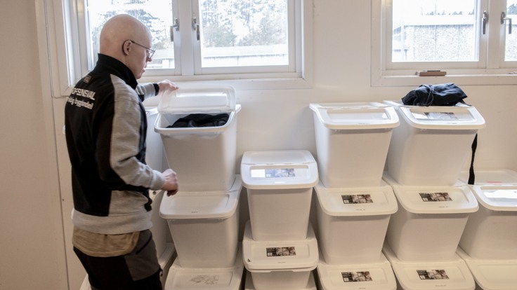 Man som står bredvid många platslådor med arbetskläder