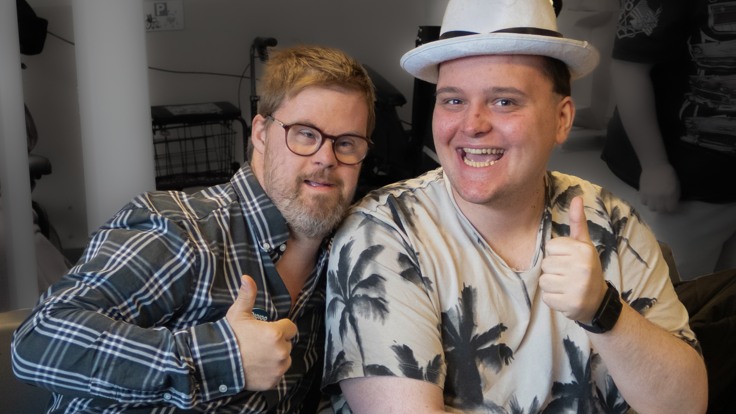 Två unga män som gör tummen-upp bredvid varandra.