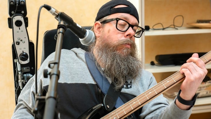 Kille med skägg som spelar gitarr
