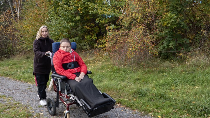 Personal och deltagare i rullstol på höstpromenad