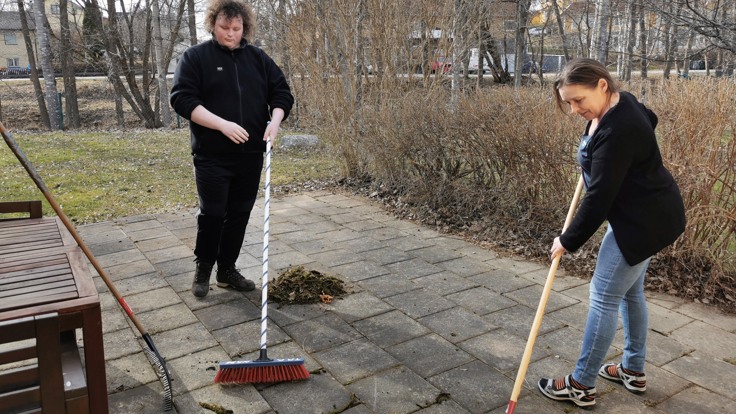 Två personer som sopar en terass