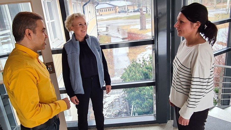Tre personer står och samtalar.